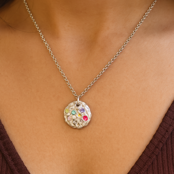 Necklace with a colorful pendant on a person wearing a brown top