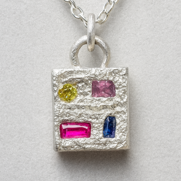 Silver pendant with colorful gemstones on a light gray background