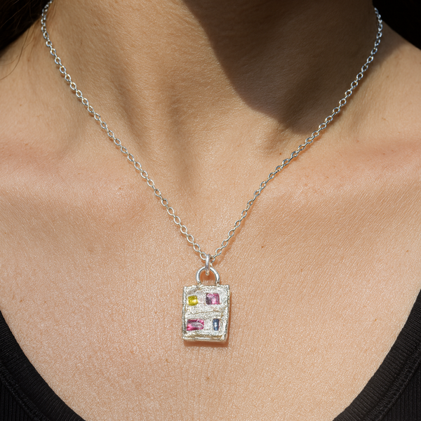 Necklace with a colorful pendant on a person wearing a black top.